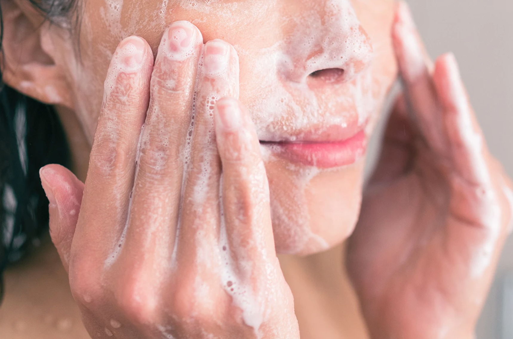 closeup of woman cleansing face with foam cleanser on her skin