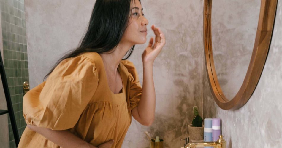 Woman applying skincare in mirror