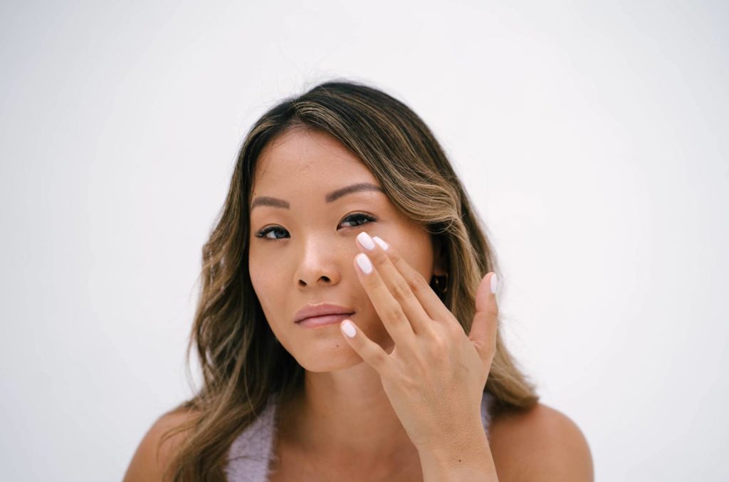 Woman applying skincare to her cheek