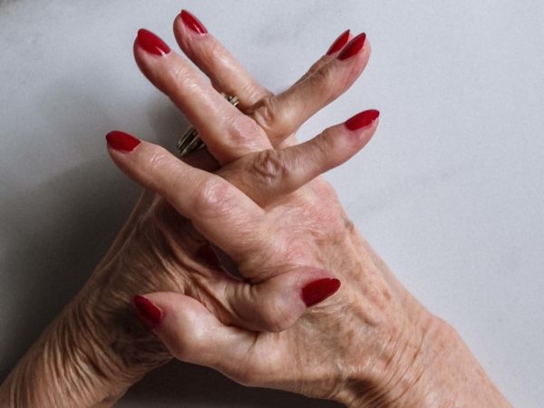 Elderly woman's hands with red nails, wrinkles and age spots