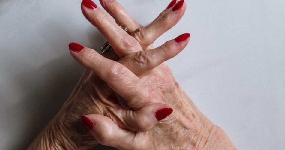 Elderly woman's hands with red nails, wrinkles and age spots